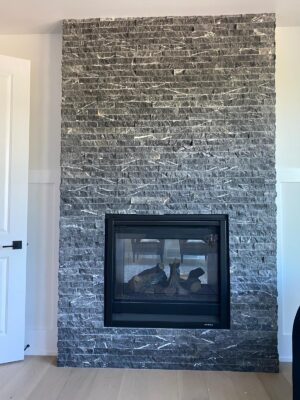 Interior fireplace and matching feature wall finished in Oro Nero splitface stone.