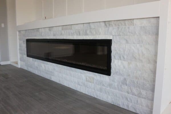 Interior horizontal fireplace finished with white marble splitface stone.
